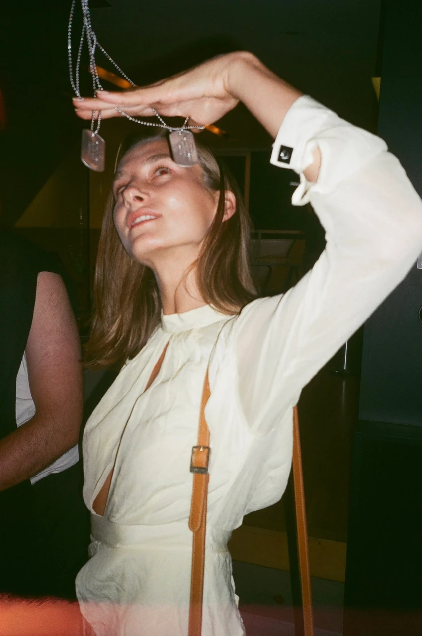 Guest holding pendants above her face at a gathering.
