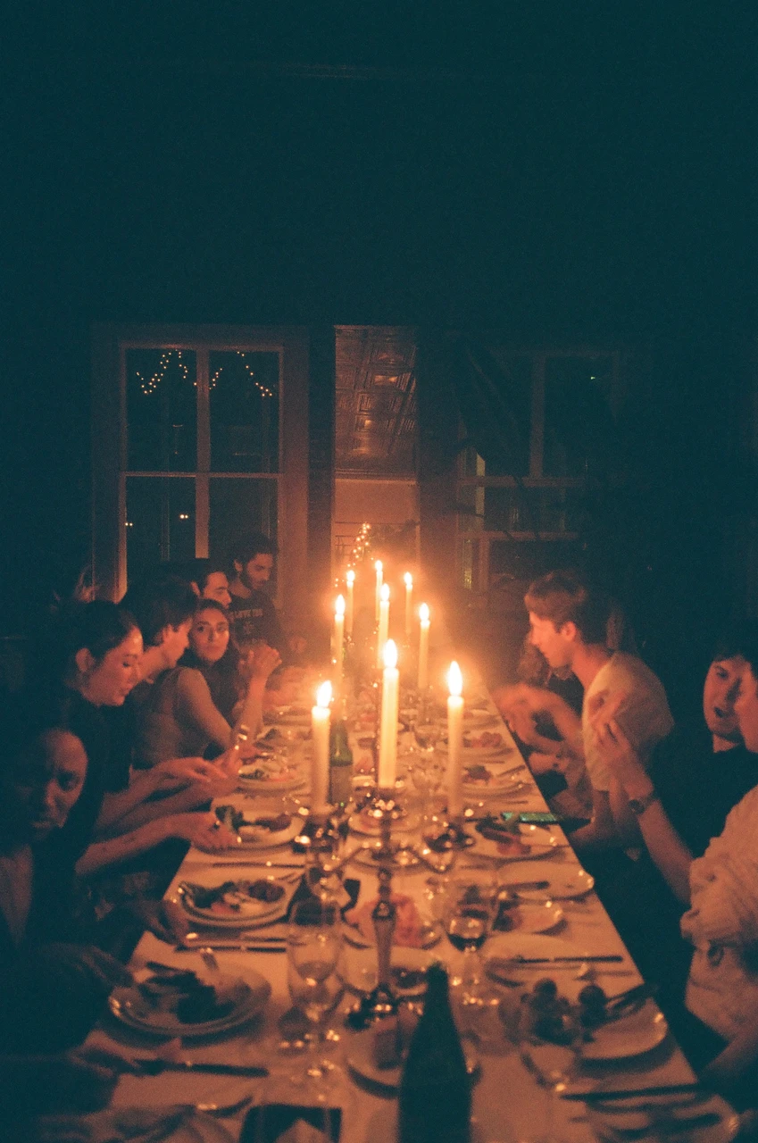 Guests seated around a long candlelit dinner table.