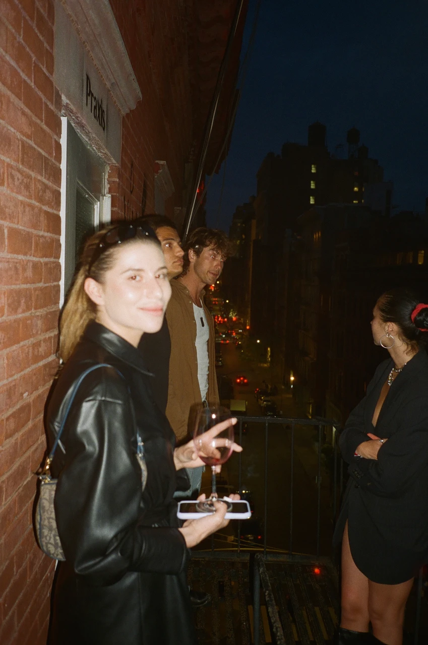 A person in a black leather jacket standing on a balcony at night.