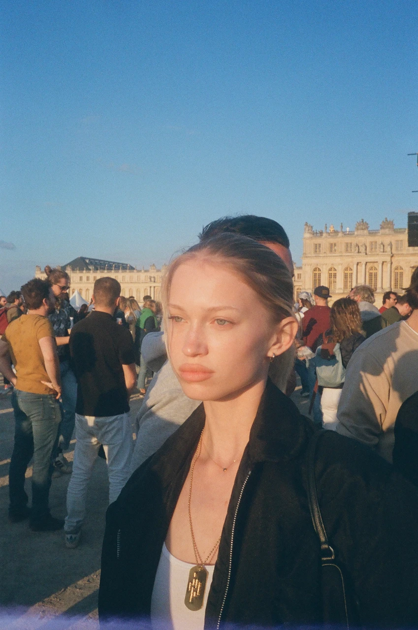 Guest wearing a pendant at an outdoor gathering in a courtyard.