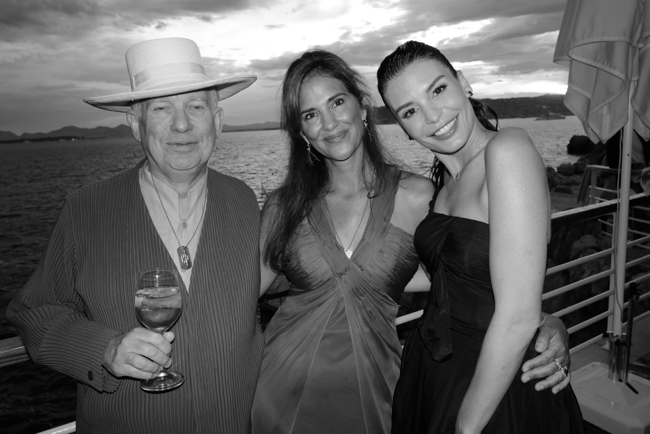 Black-and-white photograph of three guests posing on a seaside terrace.